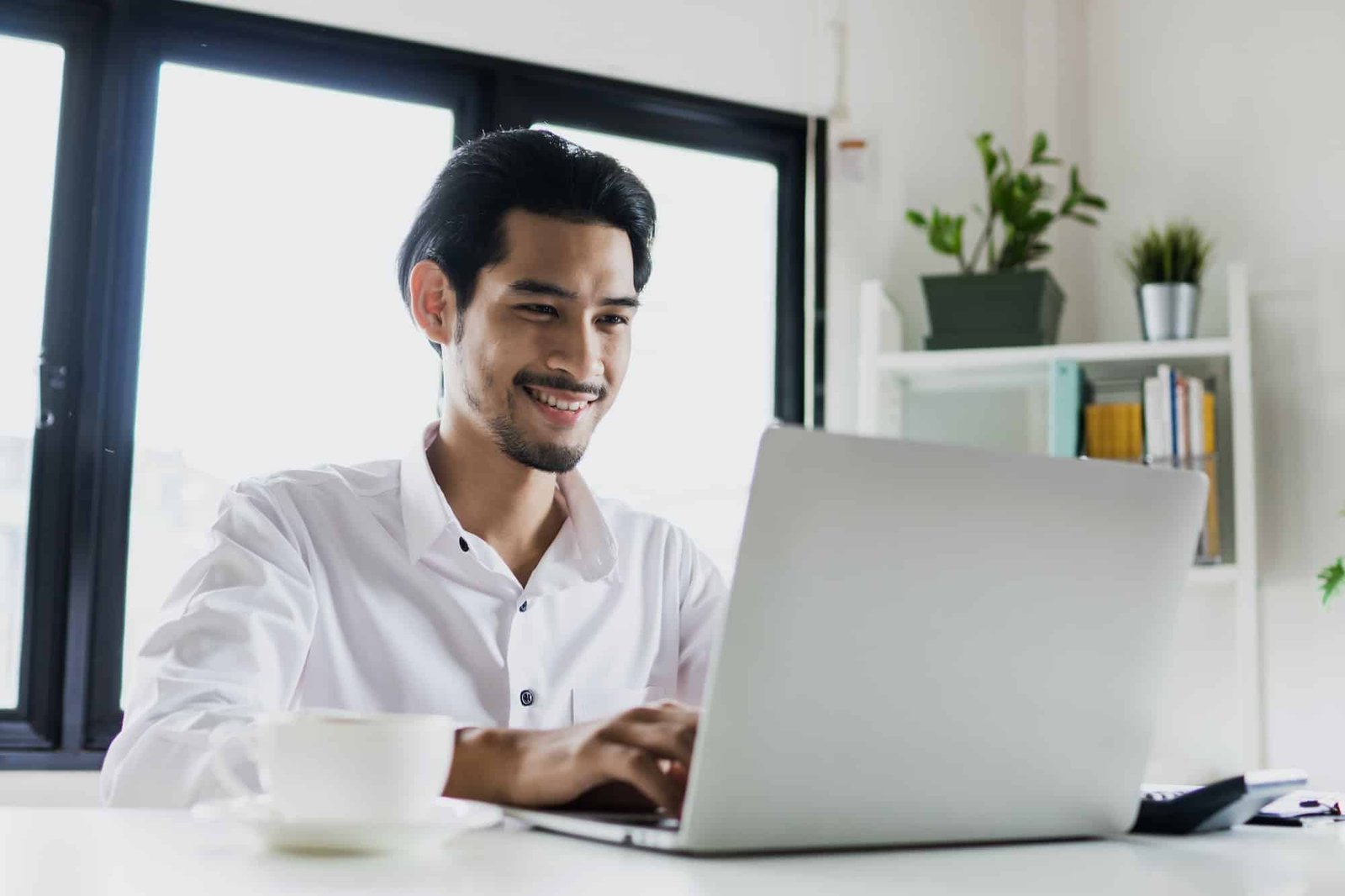 Asian Thai Business Man Working On Laptop In Office With Cup Of Coffee On Table, Golden Visa Thailand Agency