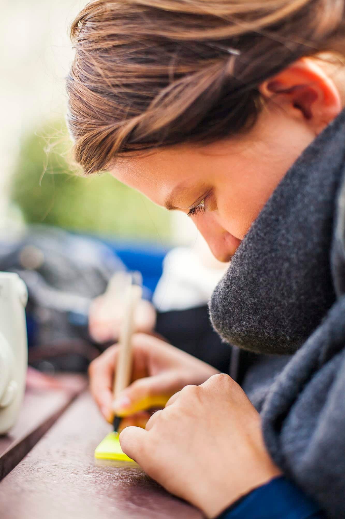 Side View Of Woman Writing On Adhesive Note Outdoors