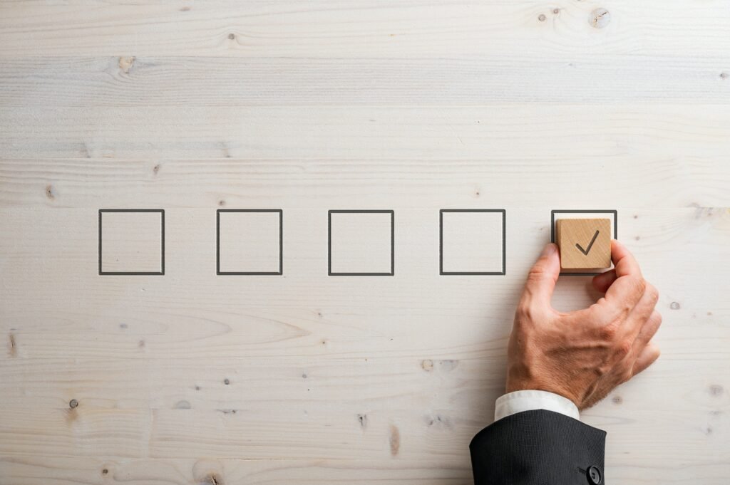 Businessman Placing Wooden Block With A Check Mark On It In A Last Check Box In The Line Of Five