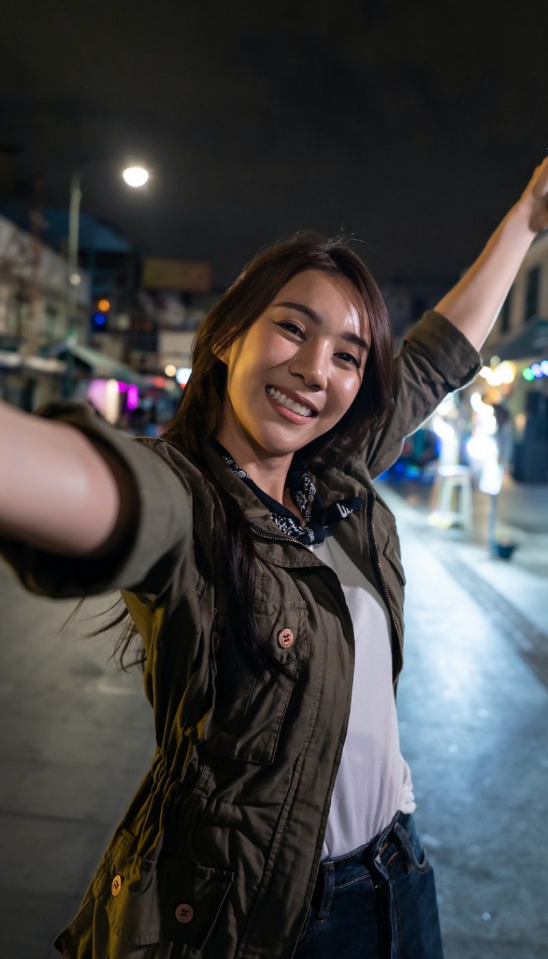 Asian woman backpacker use phone selfie, record vlog on holiday vacation trip in Thailand at night.
