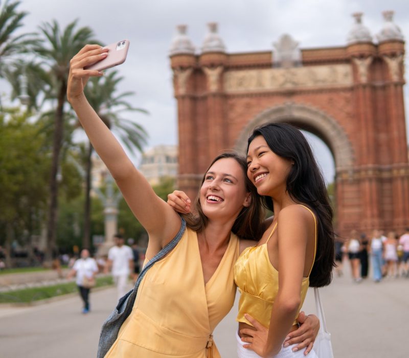 Travelling female friends taking selfie in city