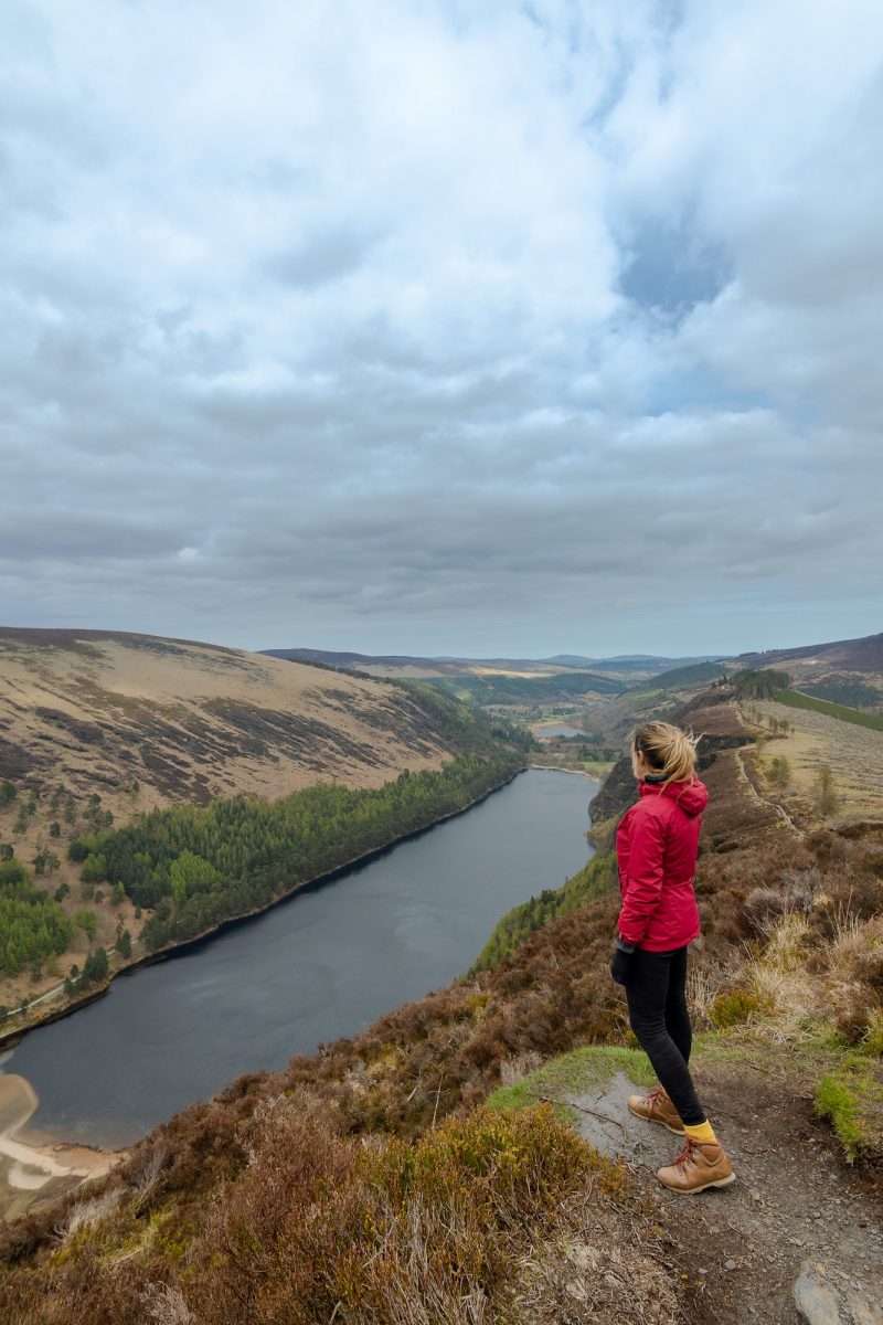 Woman traveler in a red jacket in the Spink Viewing Spot in Wicklow mountains national park, Ireland